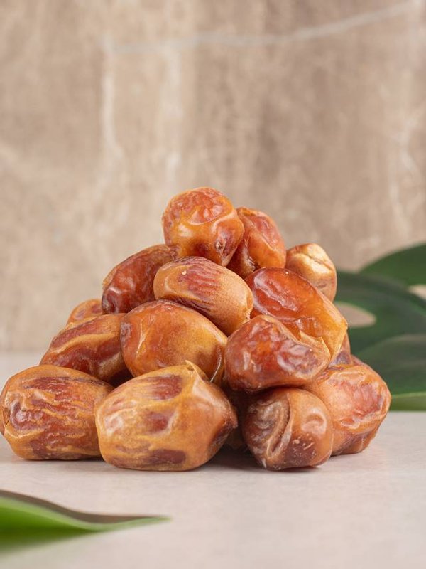 Yellow dry dates isolated on concrete background around green leaves