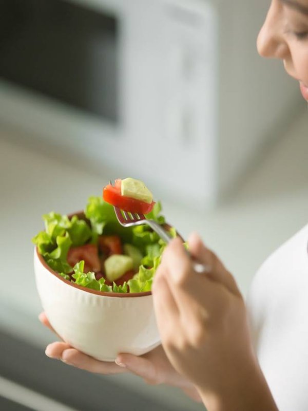 Bowl of fresh green salad hold in female hands
