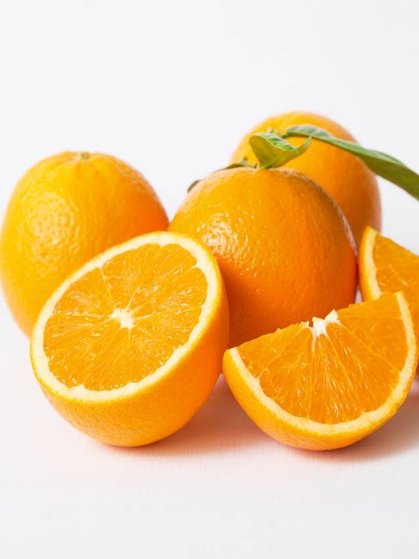 Cut and whole orange fruits with green leaves