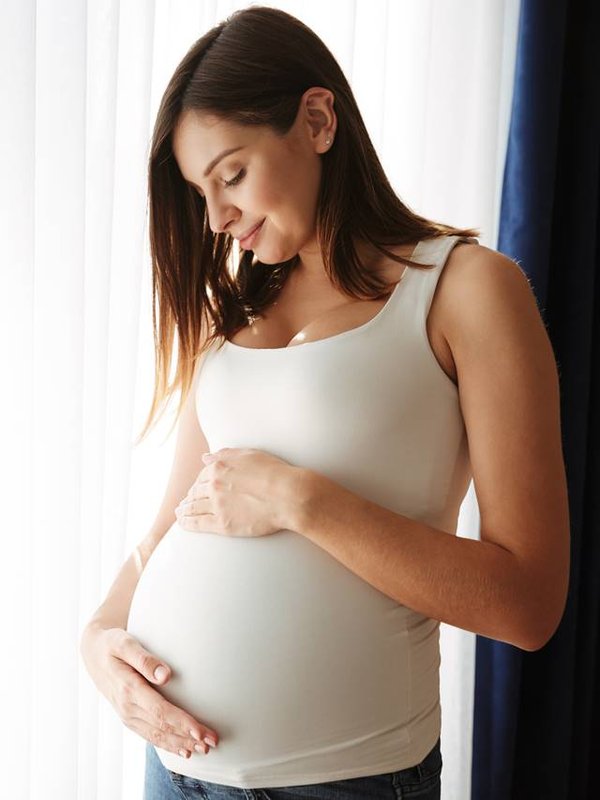 Portrait of a happy pregnant woman touching her belly