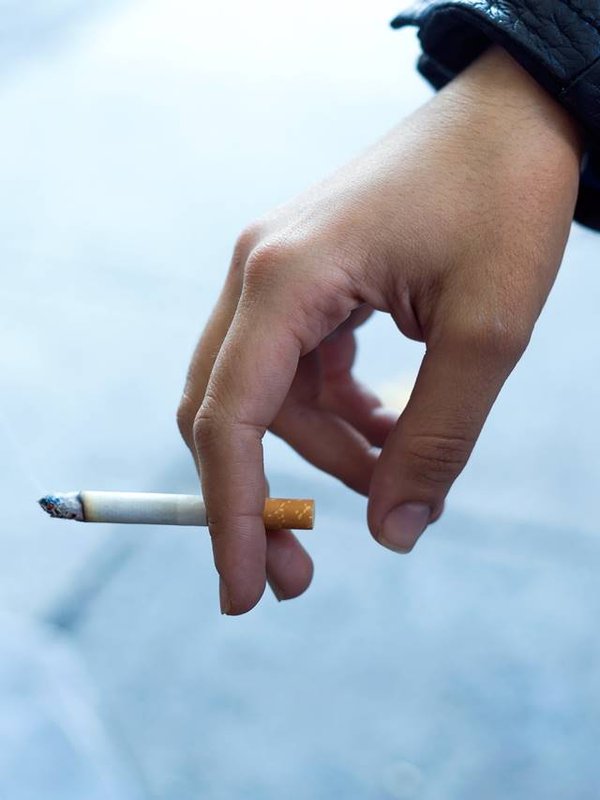 Womans hand with cigarette in the street.