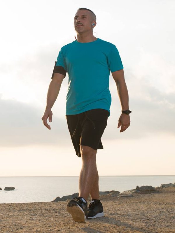 Confident male jogger walking after running
