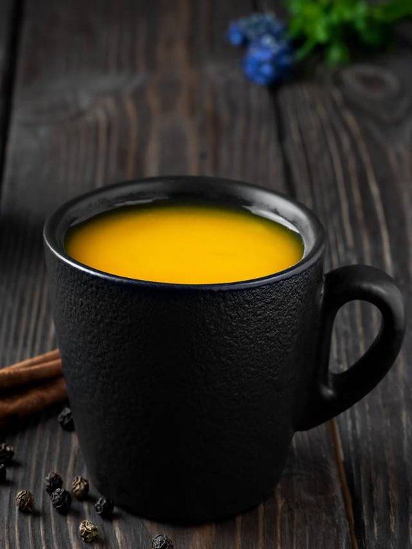 Cup with natural healthy herbal tea made from turmeric, honey and spices. Drink to support immunity against influenza and the common cold. The concept of medicine and a healthy lifestyle. Close-up
