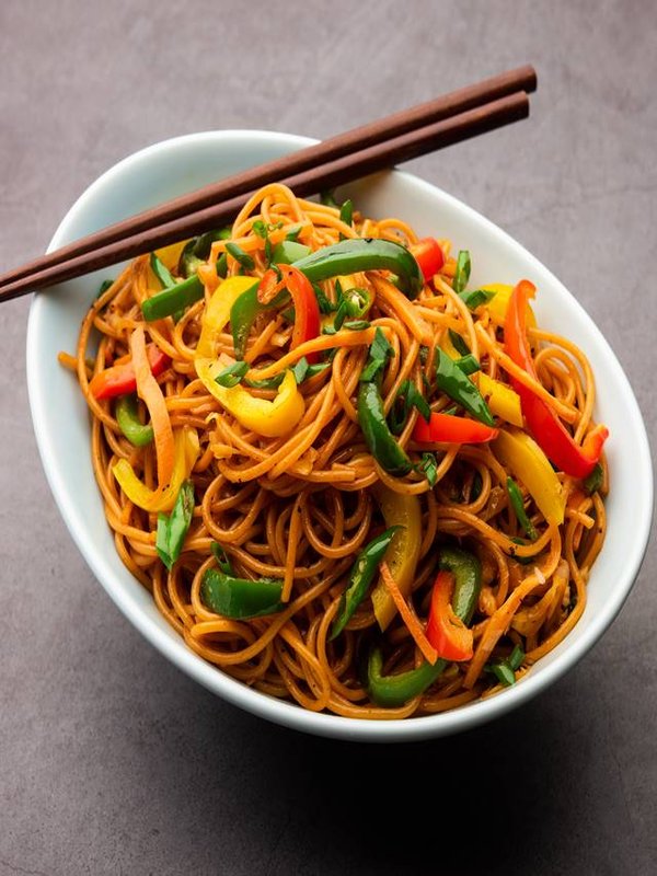 Schezwan Noodles or Szechwan vegetable Hakka Noodles or chow mein is a popular Indo-Chinese recipes, served in a bowl or plate with wooden chopsticks