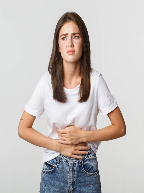 Woman having stomach ache, bending and holding hands on belly, discomfort from menstrual cramps