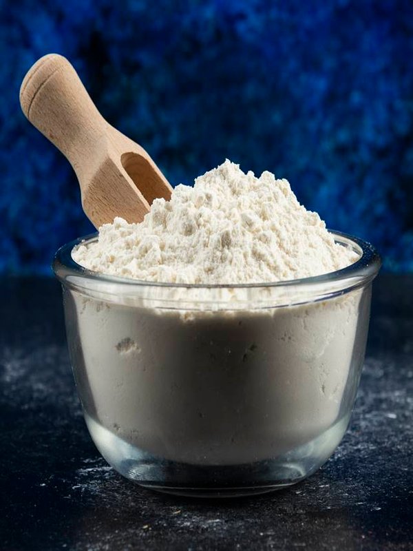 Glass bowl of flour on blue background