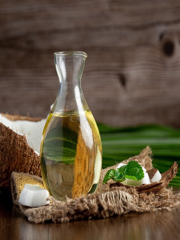 a jug of coconut oil whit coconut put on dark background