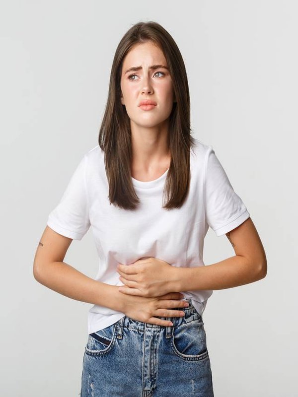 Woman having stomach ache, bending and holding hands on belly, discomfort from menstrual cramps