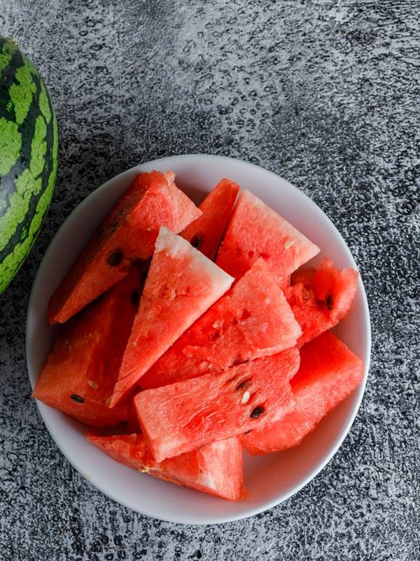 Watermelon with slices on grey grunge background, flat lay.