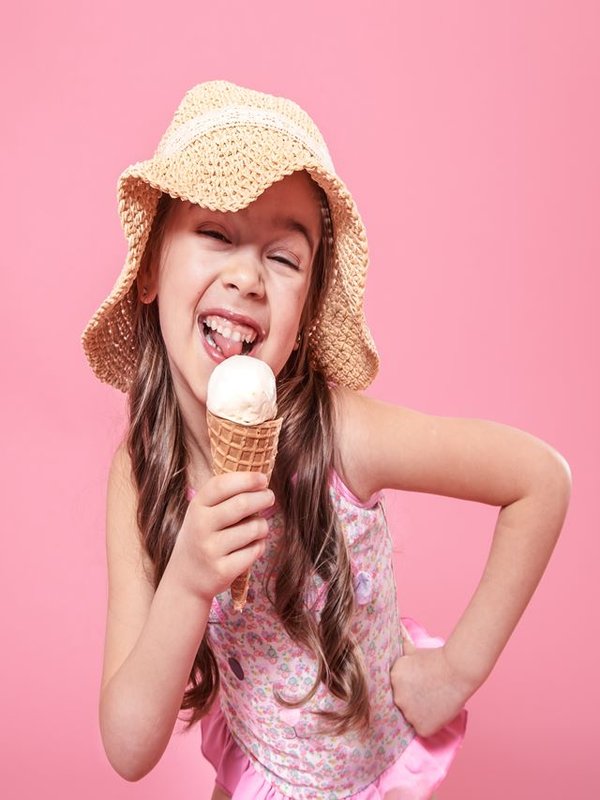 Portrait of a little cheerful girl with ice cream on a colored background