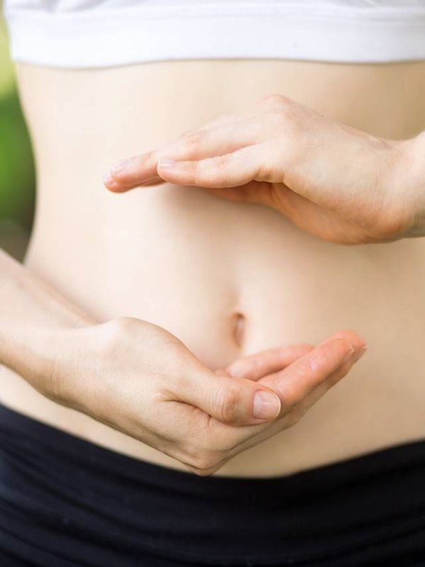 Close-up of young womans hands and slim belly