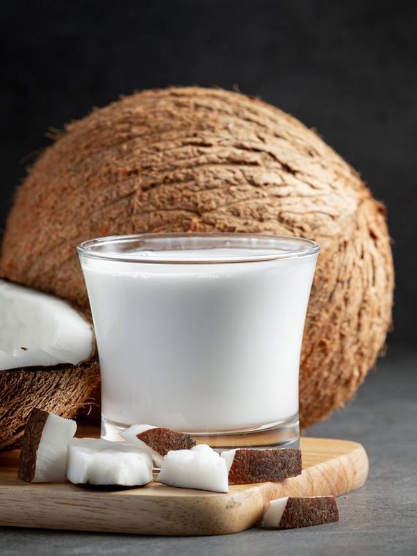 a glass of coconut milk put on wooden cutting board
