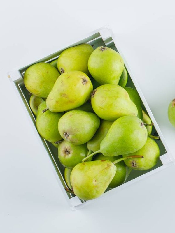 Green pears in a wooden box top view on a white background