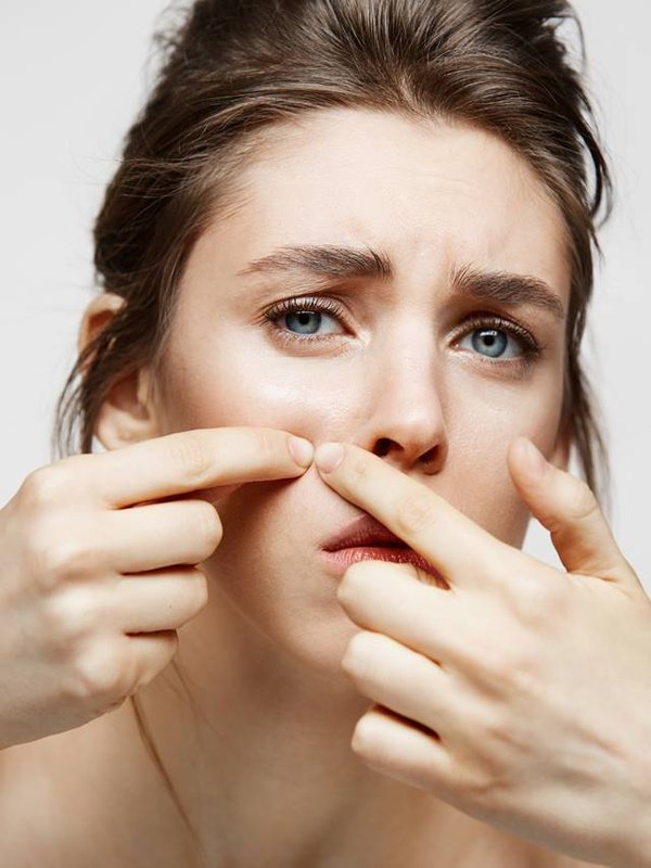 Young brunette girl displeased of her problem acne face skin over white background. Health cosmetology and skincare.