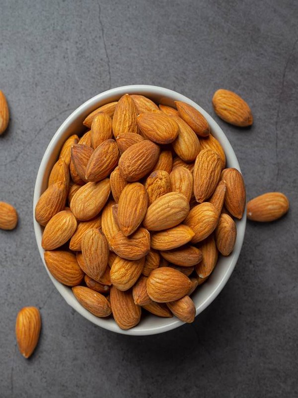 Almonds in bowl on dark background