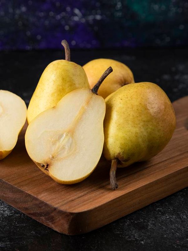 Wooden board of delicious yellow pears on black surface