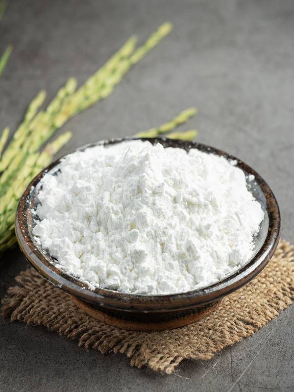 white rice flour on small bowl with rice plant