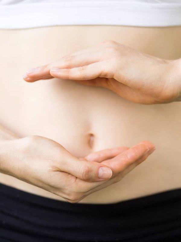 Close-up of young womans hands and slim belly