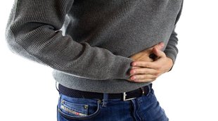 Woman having stomach ache, bending and holding hands on belly, discomfort from menstrual cramps