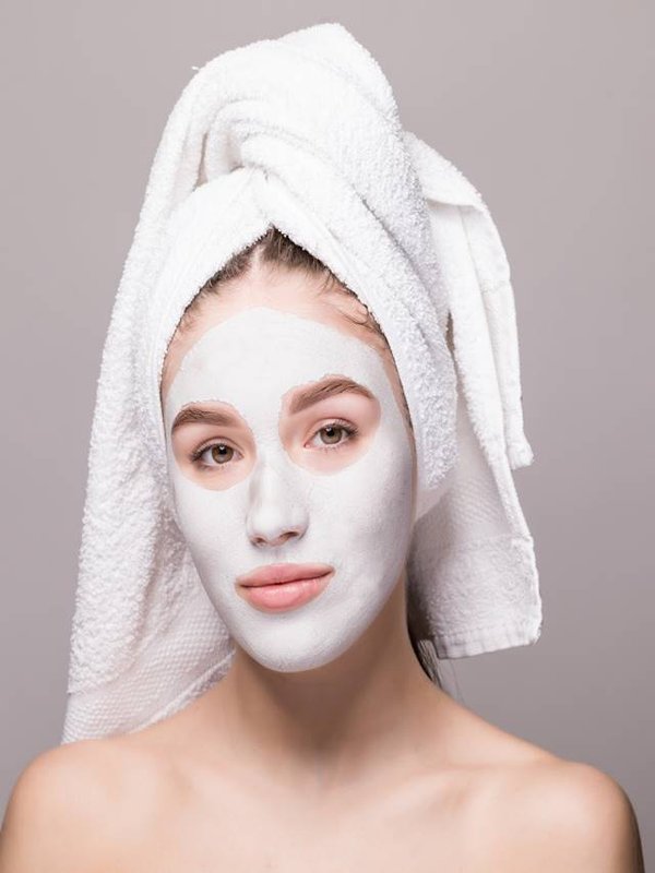 Beauty portrait of woman in towel on head with white nourishing mask or creme on face, white background isolated. Skincare cleansing eco organic cosmetic spa relax concept