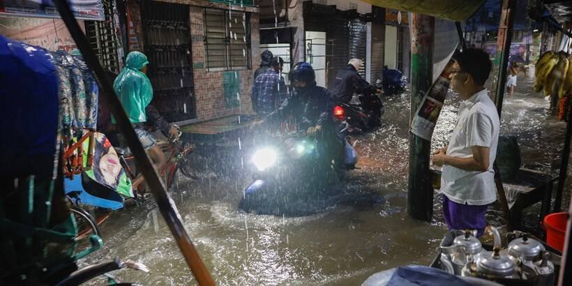 People ride rickshaws and motorcycle on a flooded street, amid continuous rain before the Cyclone Sitrang hits in Dhaka