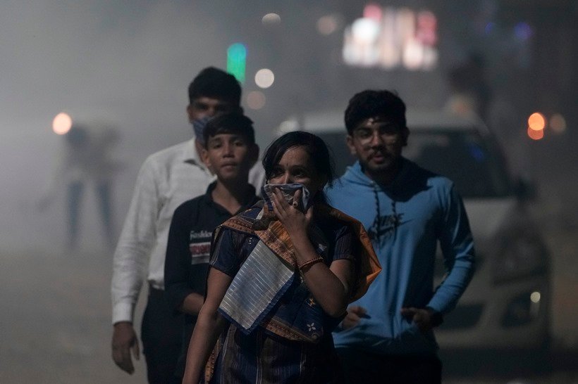 अहमदाबाद में सोमवार को दिवाली समारोह के दौरान पटाखों से निकलने वाले घने धुएं से गुजरते समय अपनी नाक ढकती हुई एक महिला। (AP)