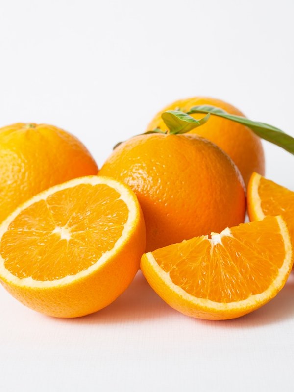 Cut and whole orange fruits with green leaves