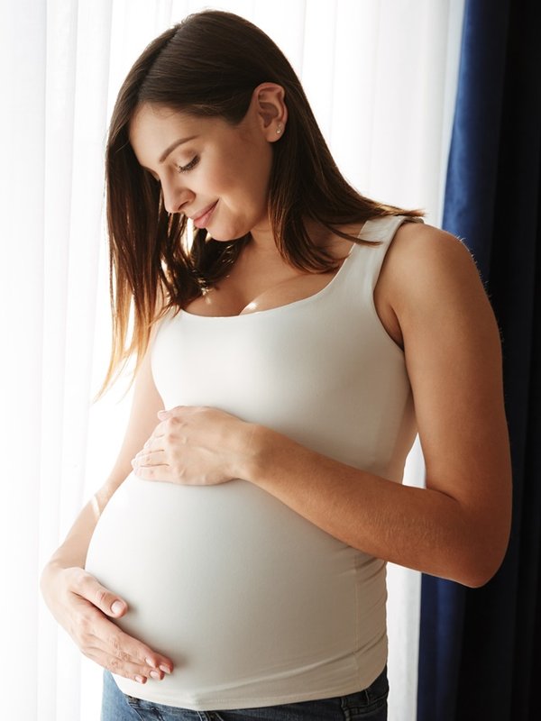 Portrait of a happy pregnant woman touching her belly