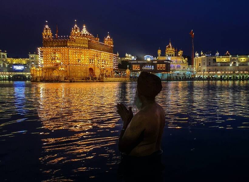 गुरुनानक जयंती के मौके पर अमृतसर के गोल्डन टेंपल के पास सरोवर में डुबकी लगाता एक श्रद्धालु। (PTI Photo)