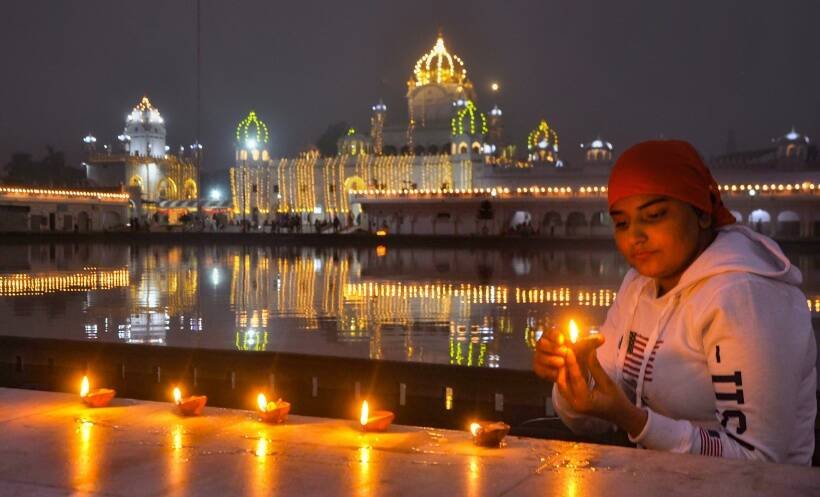 पटियाला में गुरुद्वारे के बाहर दिये जलाती एक श्रद्धालु। (PTI Photo)