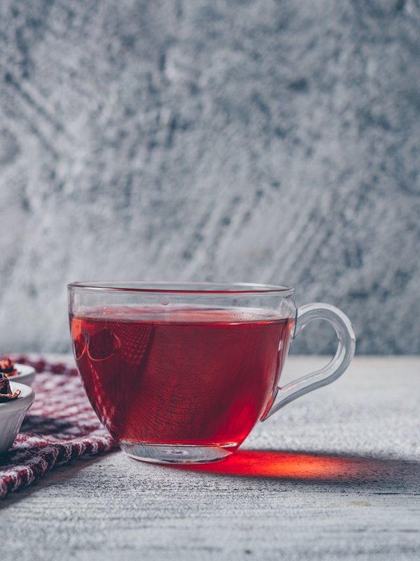 A cup of tea with tea herbs side view on a gray textured background