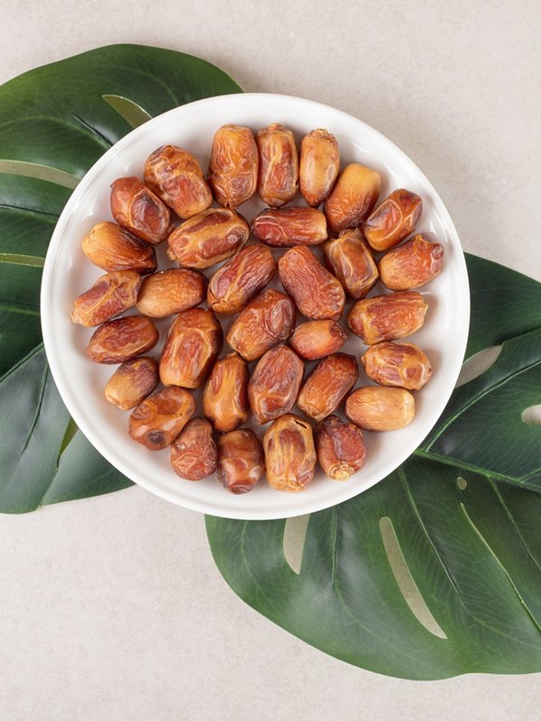 Yellow dry dates in a ceramic cup on concrete background
