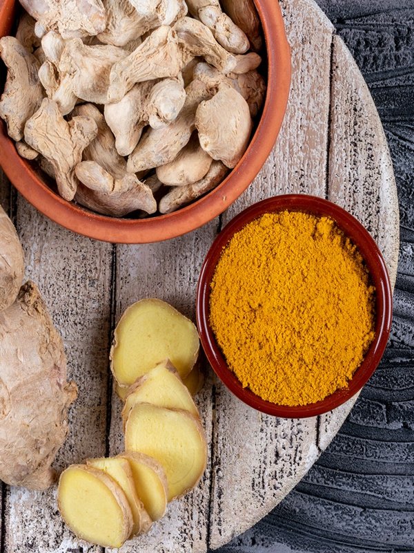 Set of ginger slices and powder and ginger in bowls on a wood and dark wooden background. top view.