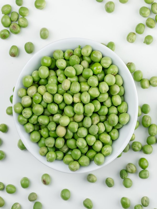 Peas in a white bowl top view on a white background
