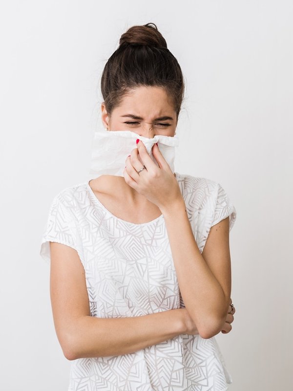 close-up portrait of pretty woman blowing her nose with napkin, catch a cold, feeling sick, isolated, white studio background, frowning