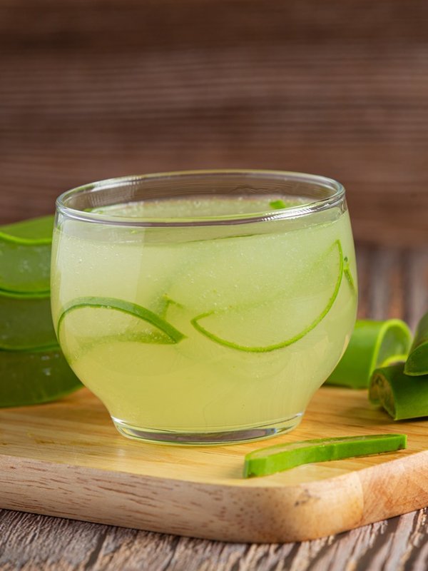 a glass of aloe vera juice put on wooden cutting board