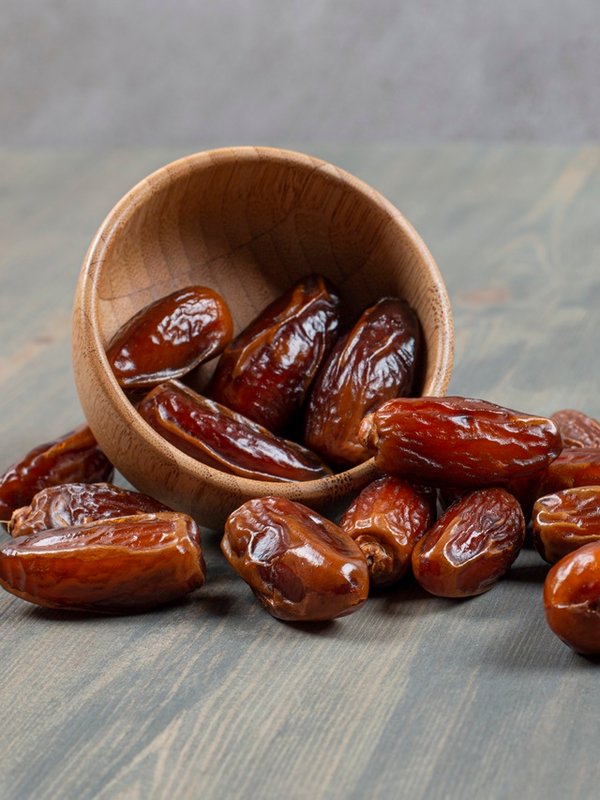 Sweet dates out of wooden bowl on marble background