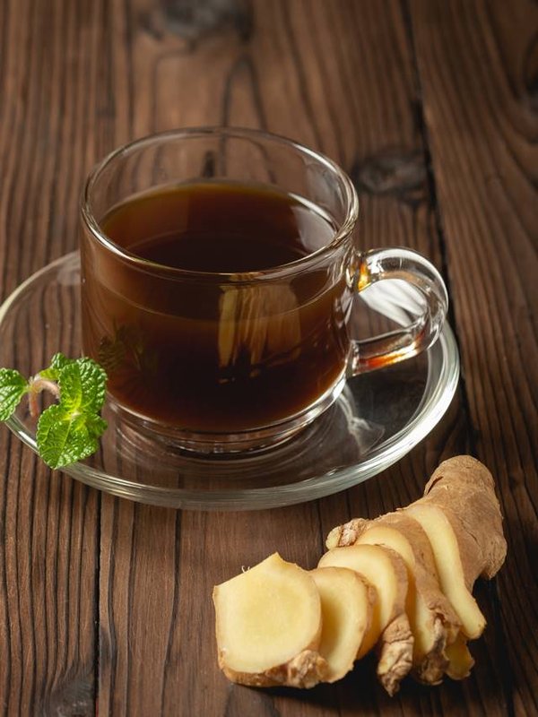 Hot ginger juice and ginger sliced on wooden table.