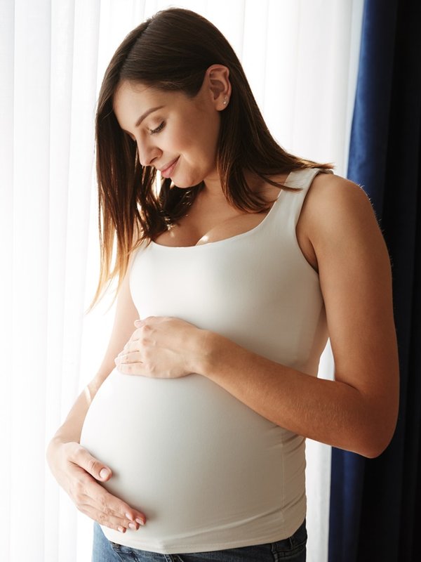 Portrait of a happy pregnant woman touching her belly