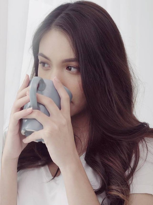 Happy beautiful Asian woman smiling and drinking a cup of coffee