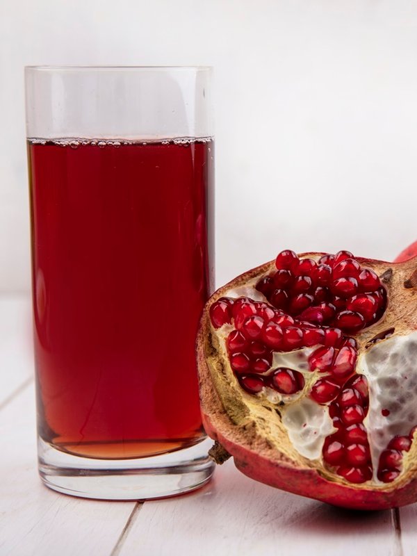 front view glass of pomegranate juice with pomegranates on white background