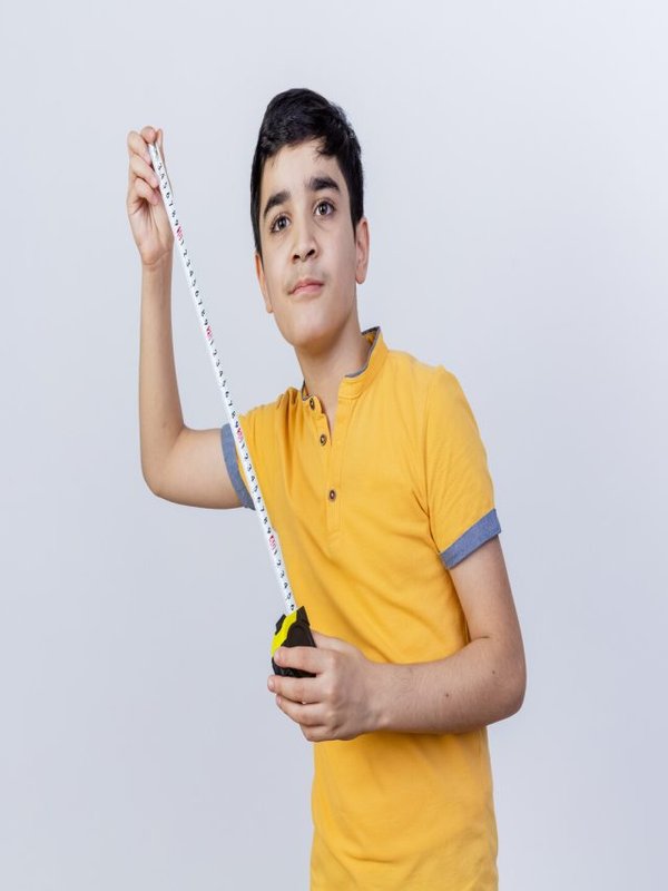 confident young caucasian boy holding tape meter looking straight isolated on white background with copy space