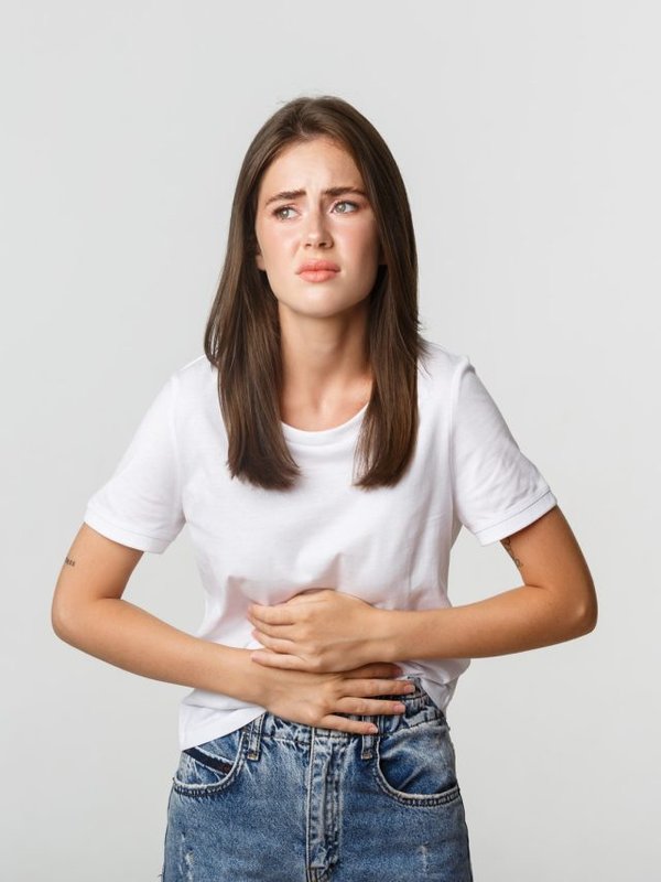 Woman having stomach ache, bending and holding hands on belly, discomfort from menstrual cramps