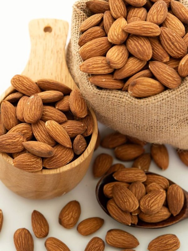 almond in a wooden spoon and bowl. Sack with almond on white bac