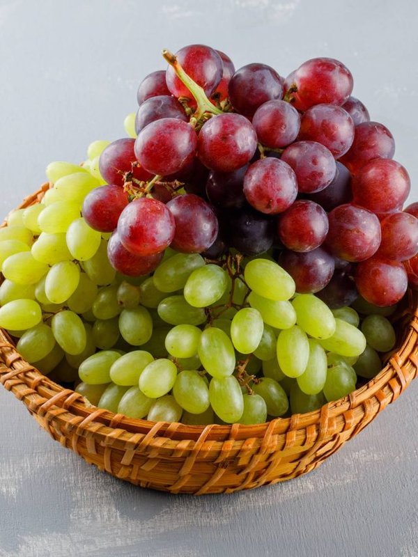 Grapes in a wicker basket high angle view on a grey plaster background
