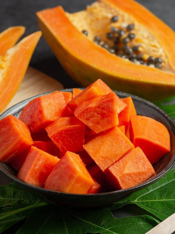 Fresh papaya, cut into pieces, put on a black plate.