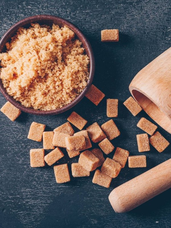 Set of herb grinder and brown sugar in a bowl on a dark background. top view.