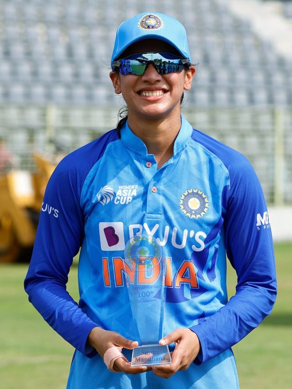 India's Smriti Mandhana poses with a memento commemorating her 100th T20I match