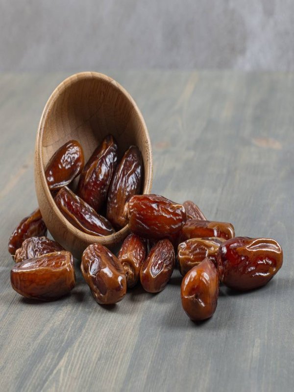 Sweet dates out of wooden bowl on marble background