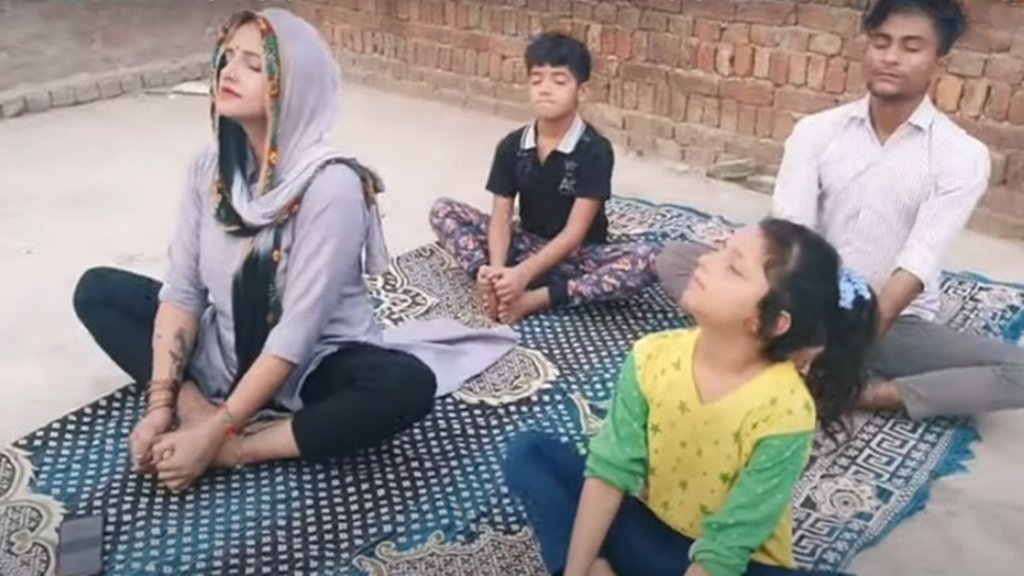 नोएडा में अपने घर की छत पर पति सचिन मीणा और बच्चों के साथ योग करतीं सीमा हैदर। (फोटो- वीडियो ग्रैब)